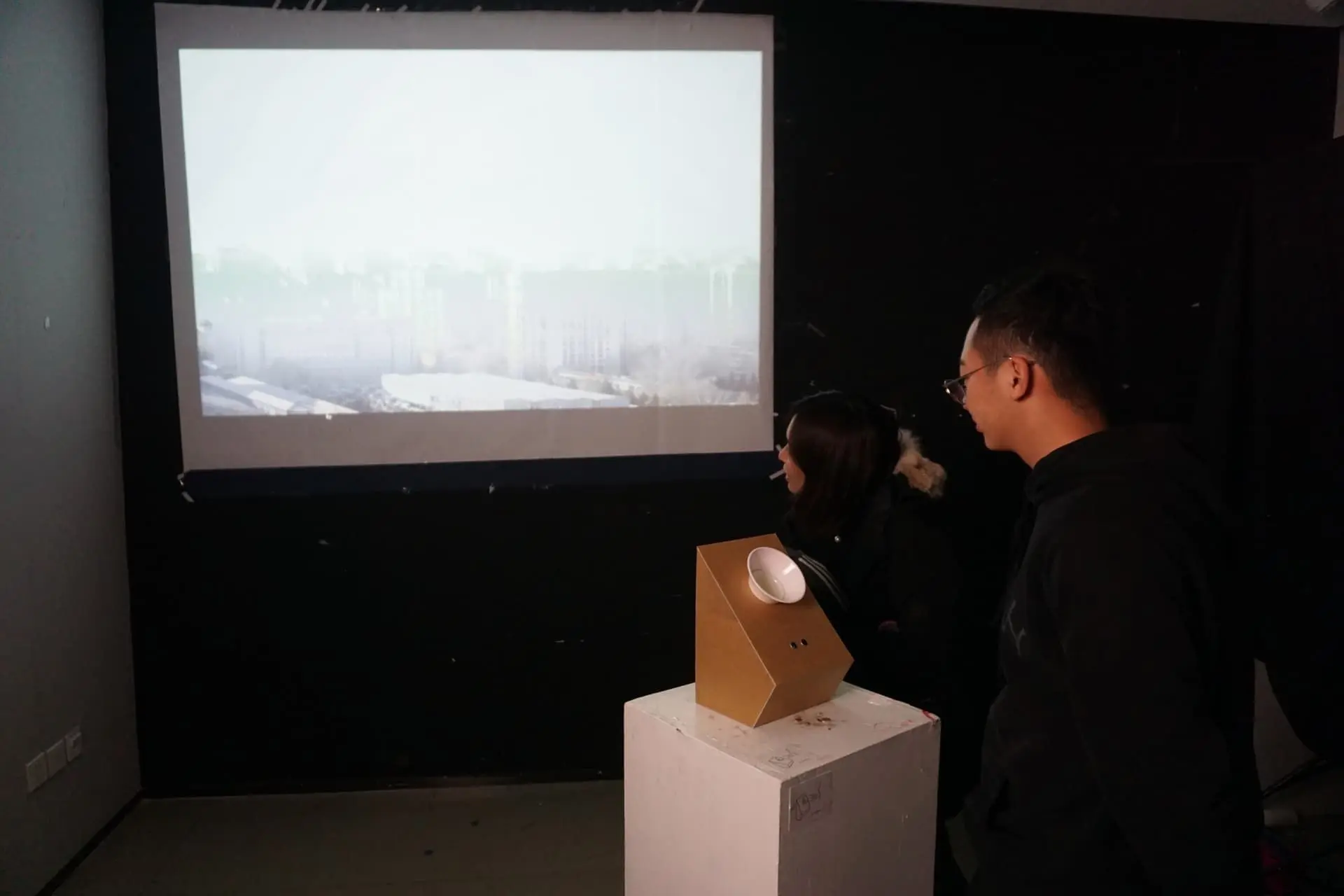 Two visitors observing the device and projection